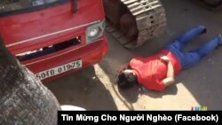 Hình ảnh một người dân nằm xuống trước xe ủi để phản đối việc cưỡng chế đất ở vườn rau Lộc Hưng. Người dân khu vực này đã không được chính quyền cho phép họp báo để công khai thông tin về việc sử dụng đất ở đây.