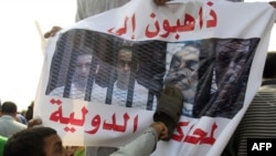 Người biểu tình dùng giày đập vào hình của cựu Tổng thống Mubarak và hình các con ông treo trước học viện cảnh sát ở Cairo nơi diễn ra phiên xử ngày 5/9/11