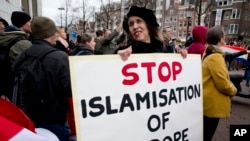 یورپ میں مسلم تارکین وطن کے خلاف مظاہرے میں ایک خاتون مسلم مخالف بینر اٹھائے ہوئے ہے۔ فائل فوٹو