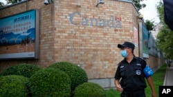 Một nhân viên an ninh mang khẩu trang canh gác bên ngoài Đại sứ quán Canada ở Bắc Kinh hôm 6/8/2020. TQ hôm 7/8 loan tin công dân Canada thứ nhì bị kết án tử hình trong 2 ngày. (AP Photo/Mark Schiefelbein)