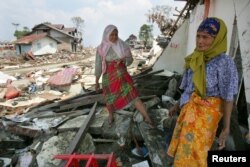 انڈونیشیا میں زلزلے سے بڑے پیمانے کی تباہی کے بعد خواتین اپنے گھروں میں بچ جانے والی چیزیں ڈھونڈ رہی ہے۔ 2010