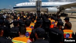 Các công dân Trung Quốc bị tình nghi lừa đảo tống tiền qua mạng (áo khoác da cam) được cảnh sát Trung Quốc áp tải chờ lên máy bay tại Sân bay Quốc tế Phnom Penh, ở Phnom Penh, Campuchia, ngày 12 tháng 10, 2017.
