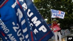 Người ủng hộ Tổng thống Donald Trump và cựu Phó Tổng thống Joe Biden vẫy cờ và biển bên ngoài một điểm bầu cử sớm tổng thống Mỹ. Số lượng cử tri họ Nguyễn dẫn đầu trong số những người dân Mỹ bỏ phiếu sớm cho kỳ bầu cử này ở hạt Harris lớn nhất của Texas.